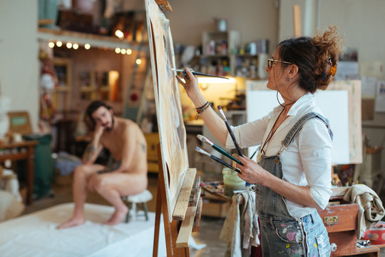 Artist woman drawing a model in her studio.