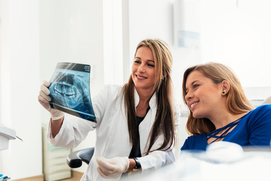 Doctor talking with her patient and teaching a radiography.