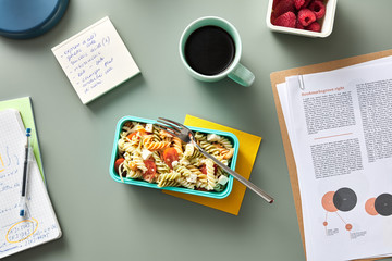 Workplace with homemade lunch and cup of coffee with raspberries