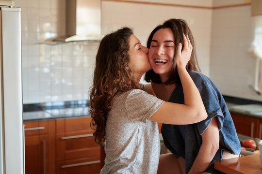 Happy kissing girls in kitchen