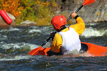 Fototapeta premium Whitewater kayaking on fast moving water of mountain river among the rapids, extreme water sport. Kayak freestyle on whitewater. Man in red kayak