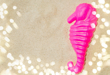 Fototapeta na wymiar toys, childhood and vacation concept - close up of pink sea horse mold on summer beach sand