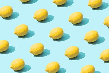 Trendy sunlight Summer pattern made with yellow lemon on bright light blue background. Minimal...