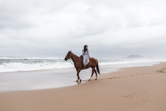 A girl riding a horse on the beach