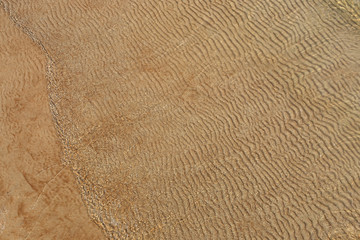 Fototapeta na wymiar Sand texture created by sea waves on beach coast. Top view of sand pattern under soft waves. Sand texture of Baltic sea coast.