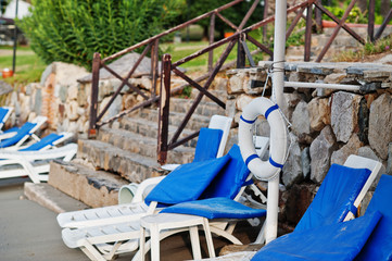 Lifebuoy with blue sunbeds at empty beach.