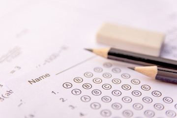 Pencil and eraser on answer sheets or Standardized test form with answers bubbled. multiple choice answer sheet .