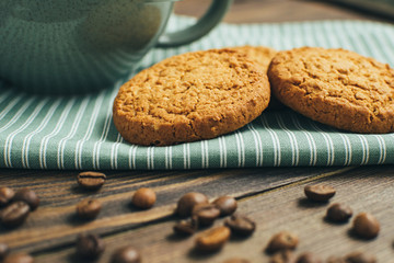 Healthy diet breakfast with oatmeal cookies at green kitchen napkin and coffee beans at wooden background,close-up