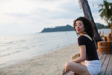 Asian woman sitting on the tropical sea beach.