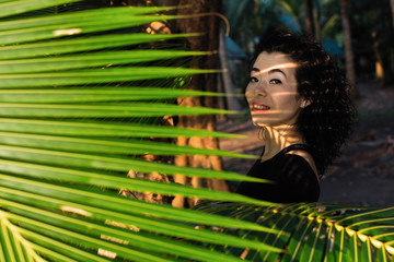 Asian woman among the leaves of palm trees.