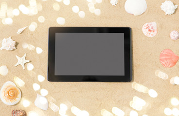 technology, vacation and summer holidays concept - tablet computer and seashells on beach sand