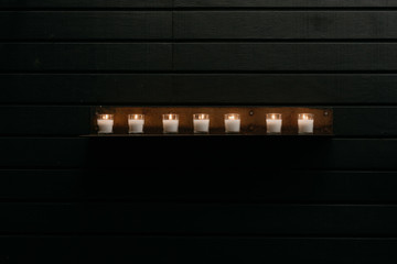 A Row of Small Candles on a Dark Wall