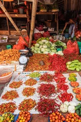 Fotobehang Makassar, Sulawesi, Indonesia - February 28, 2019: Terong Street Market. Colorful display on white tarp of variety of chili peppers. Other veggies and legumes around. © Klodien