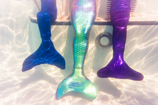 Family on Florida vacation sits in swimming pool wearing mermaid tail costume