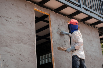 Construction workers plastering building wall using cement plaster