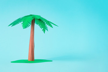 Palm tree made of paper on pastel blue background. Minimal summer beach concept.