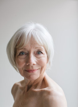 Senior topless woman on simple grey background