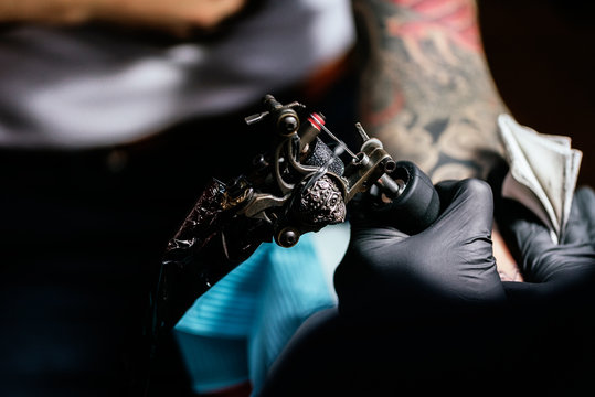 Closeup of asian tattooer makes a tattoo