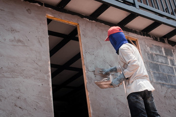 Construction workers plastering building wall using cement plaster