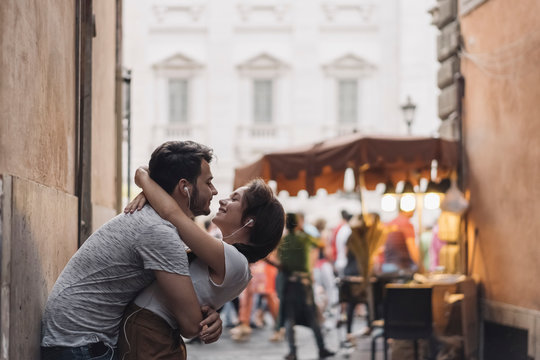 Young Couple Listening Music on the Headphones and kissing in th