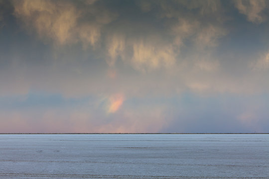 Clearing storm and small rainbow over salt flats at dusk, Bonneville, Utah