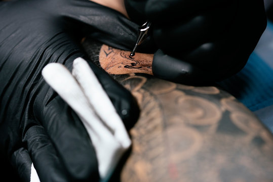 Closeup of asian tattooer makes a tattoo