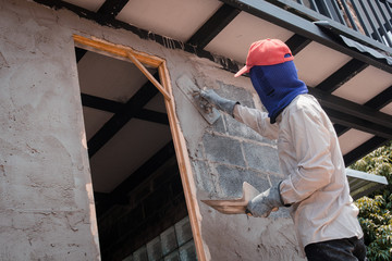 Construction workers plastering building wall using cement plaster