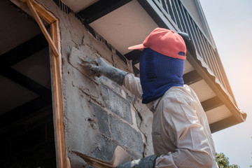 Construction workers plastering building wall using cement plaster