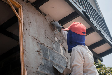 Construction workers plastering building wall using cement plaster