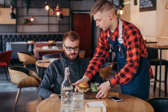 Waiter serving burger to a man