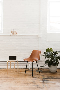 white brick wall studio with leather chair, speaker and potted plant