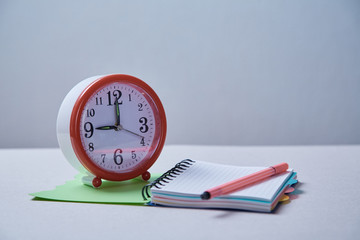 Fototapeta na wymiar Time management, deadline and schedule concept: alarm clock and notebook on blue background.