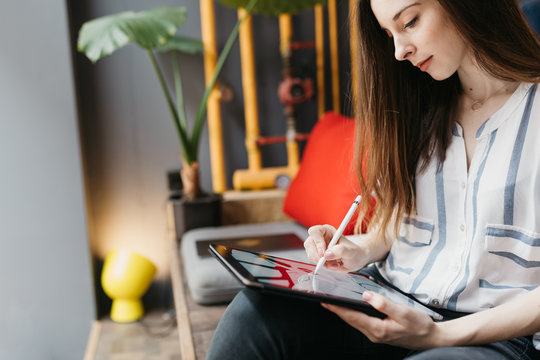 Brunette woman drawing on a tablet in the offce