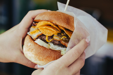 tasty burger. stylish hipster woman holding juicy hamburger in hands close up.