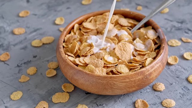 Milk is poured into crispy flakes. Healthy breakfast. Wooden dishes