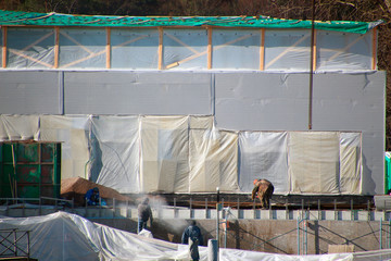 construction workers working on a construction site with walls covered with protective film