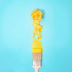 Paint brush with yellow rose flower and petals. Minimal spring concept. Nature flat lay.