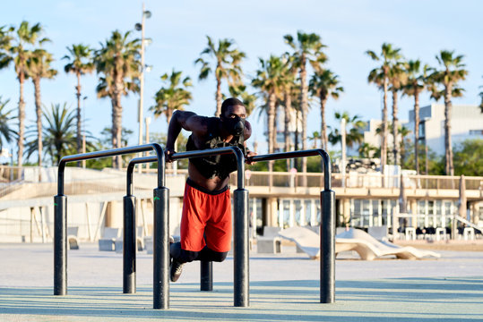 Strong man in respiratory mask and vest performing triceps dips.