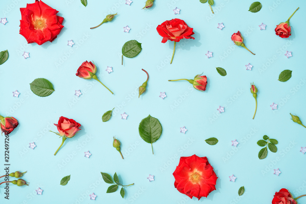 Poster creative arrangement of red flowers and leaves on pastel blue background. blooming rose concept. fla