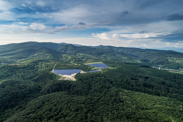 Fototapeta premium Solar panels in the woods in the mountains. Picture taken with a drone.