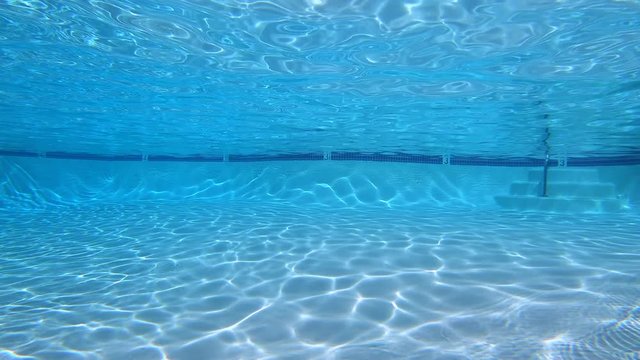 Underwater sunlight patters in clean, empty suburban swimming pool.  