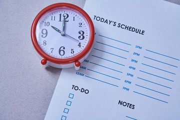 Time management deadline and schedule concept: alarm clock on the background of the schedule.