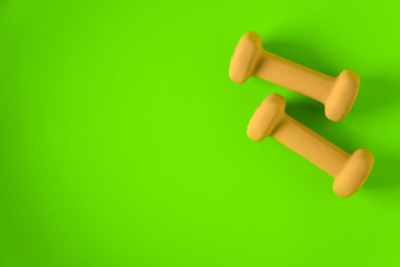 Fitness equipment with womens yellow weights/ dumbbells isolated on a lime green background with copyspace