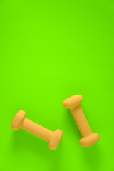 Fitness equipment with womens yellow weights/ dumbbells isolated on a lime green background with copyspace