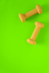 Fitness equipment with womens yellow weights/ dumbbells isolated on a lime green background with copyspace