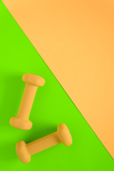Fitness equipment with womens yellow weights/ dumbbells isolated on a lime green and yellow pink background with copyspace