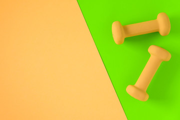 Fitness equipment with womens yellow weights/ dumbbells isolated on a lime green and yellow pink background with copyspace