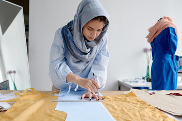 Woman outlining pattern on dress fabric