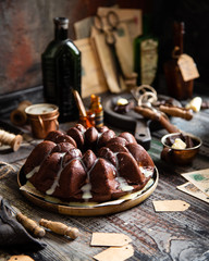 Delicious homemade chocolate bundt cake on wooden plate stands on rustic table