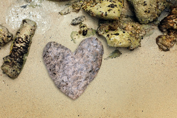 close up heart shaped stone on sandy beach